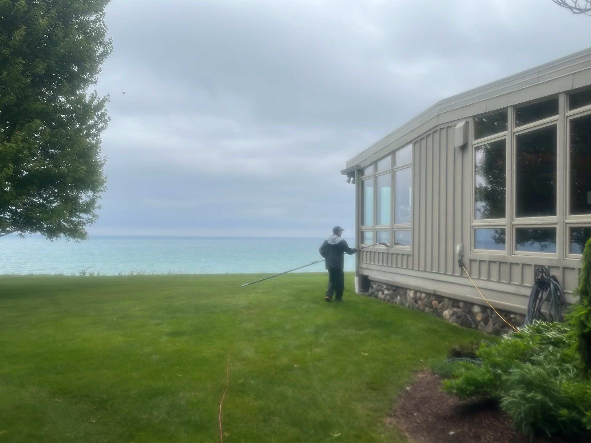 Photo of blue water on Lake Michigan with an employee cleaning windows in the rain.